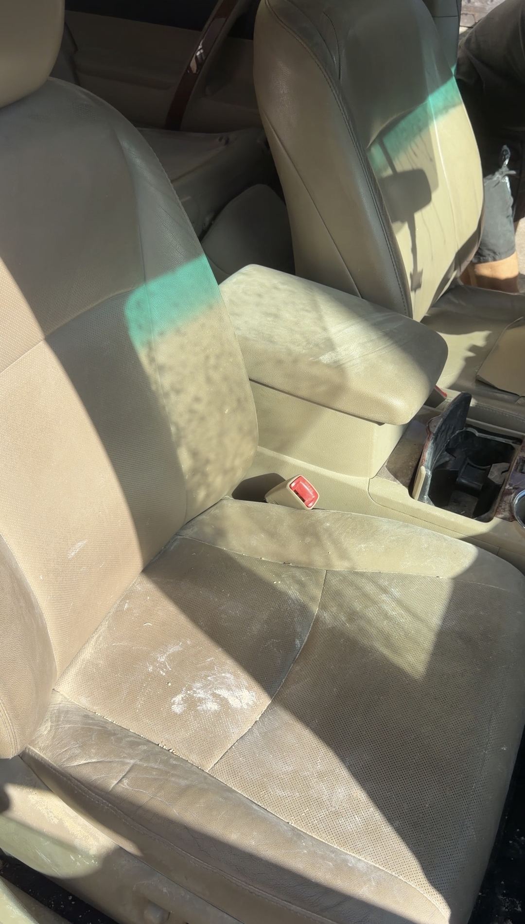 Tan leather front seat of a Toyota Highlander marked with pale dust before cleaning