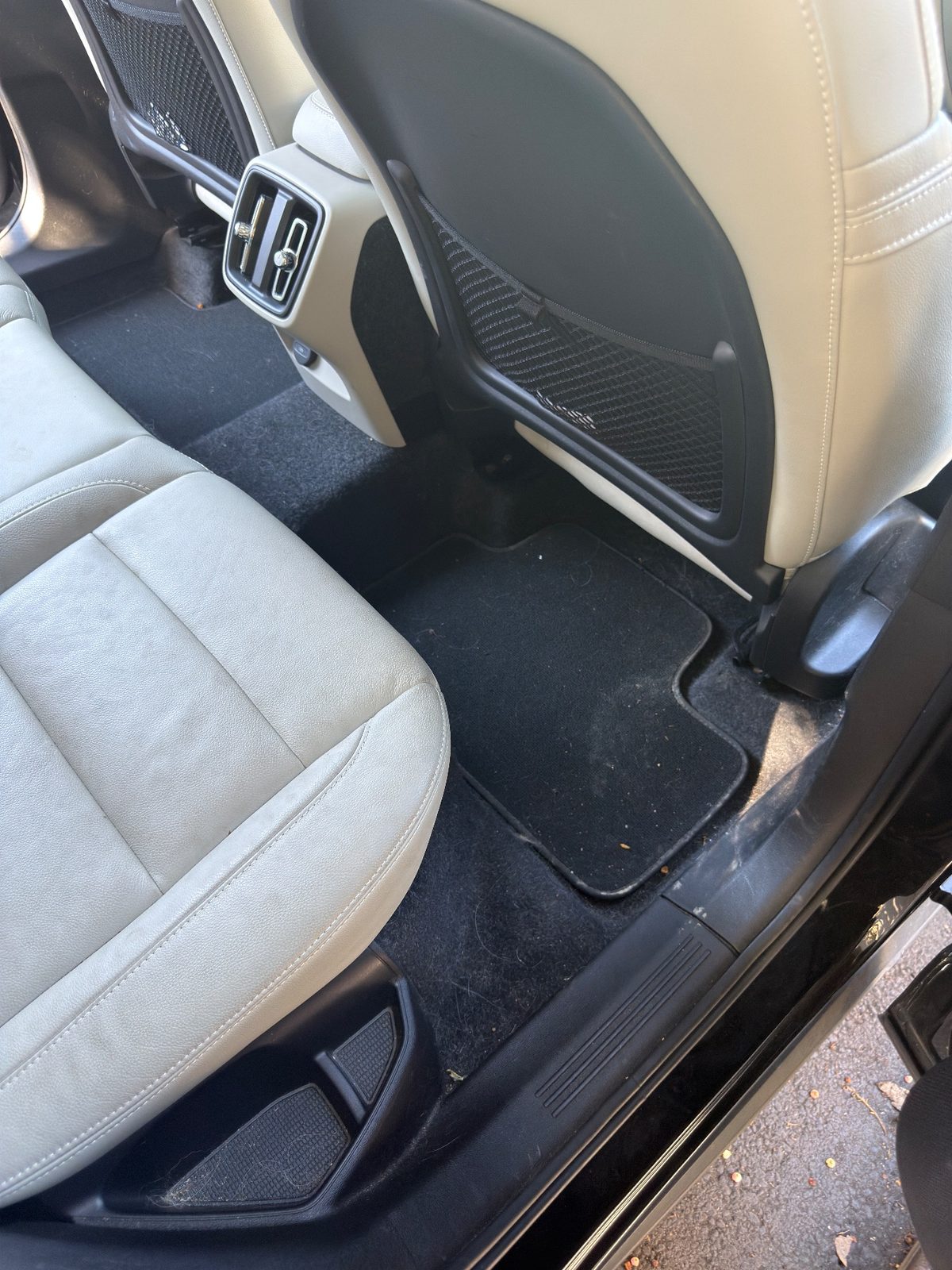 Rear footwell of a Volvo XC40 before detailing, with hair, fluff and grit on the mat and sill