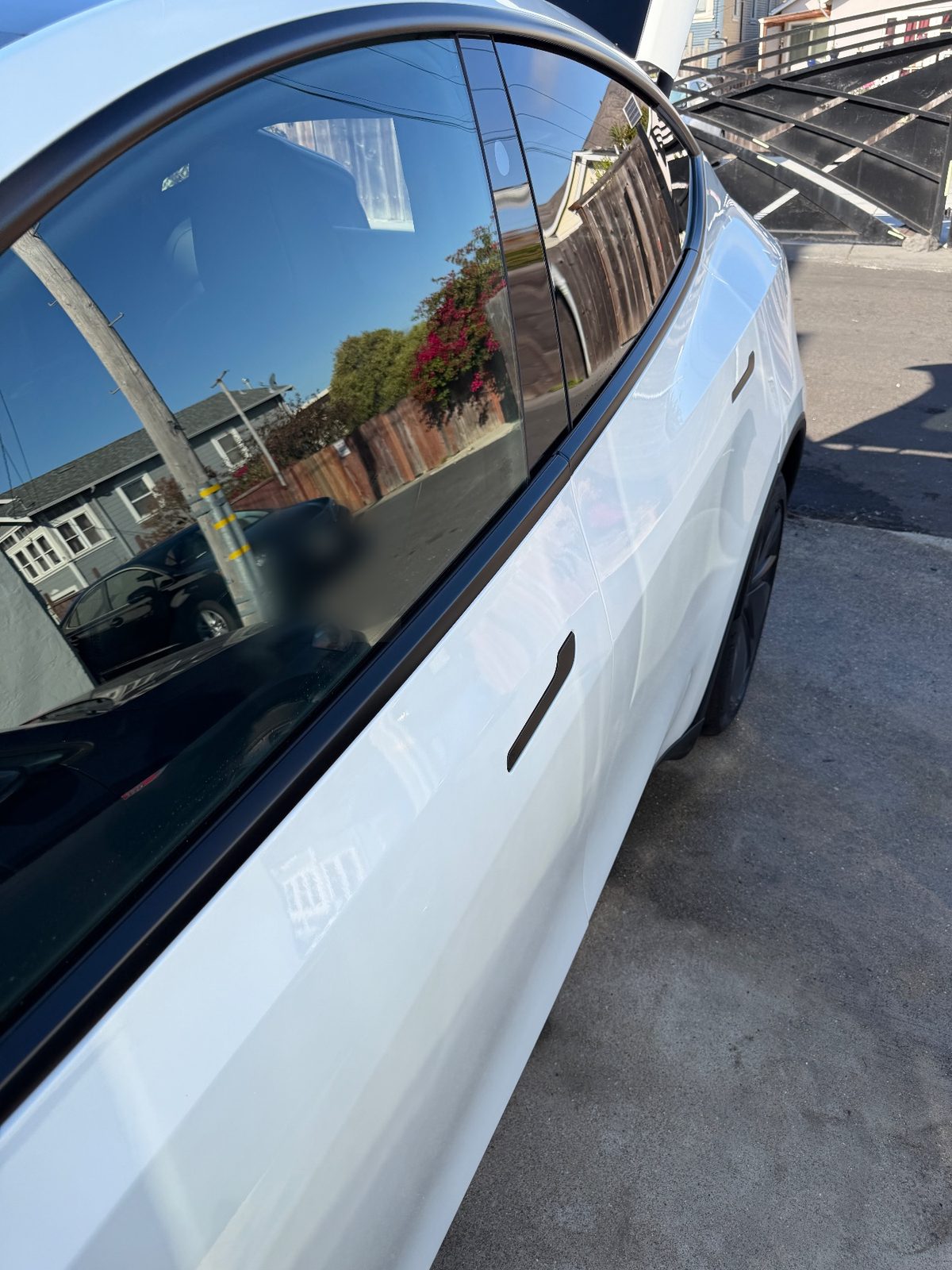 Clean glossy rear door and window of a white Tesla Model Y after detailing