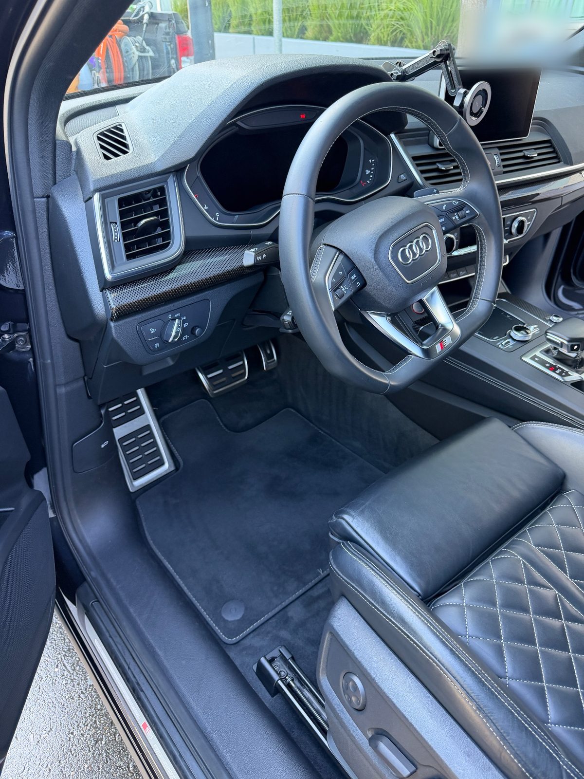 Driver footwell and steering wheel of an Audi SQ5 after detailing, with a vacuumed mat