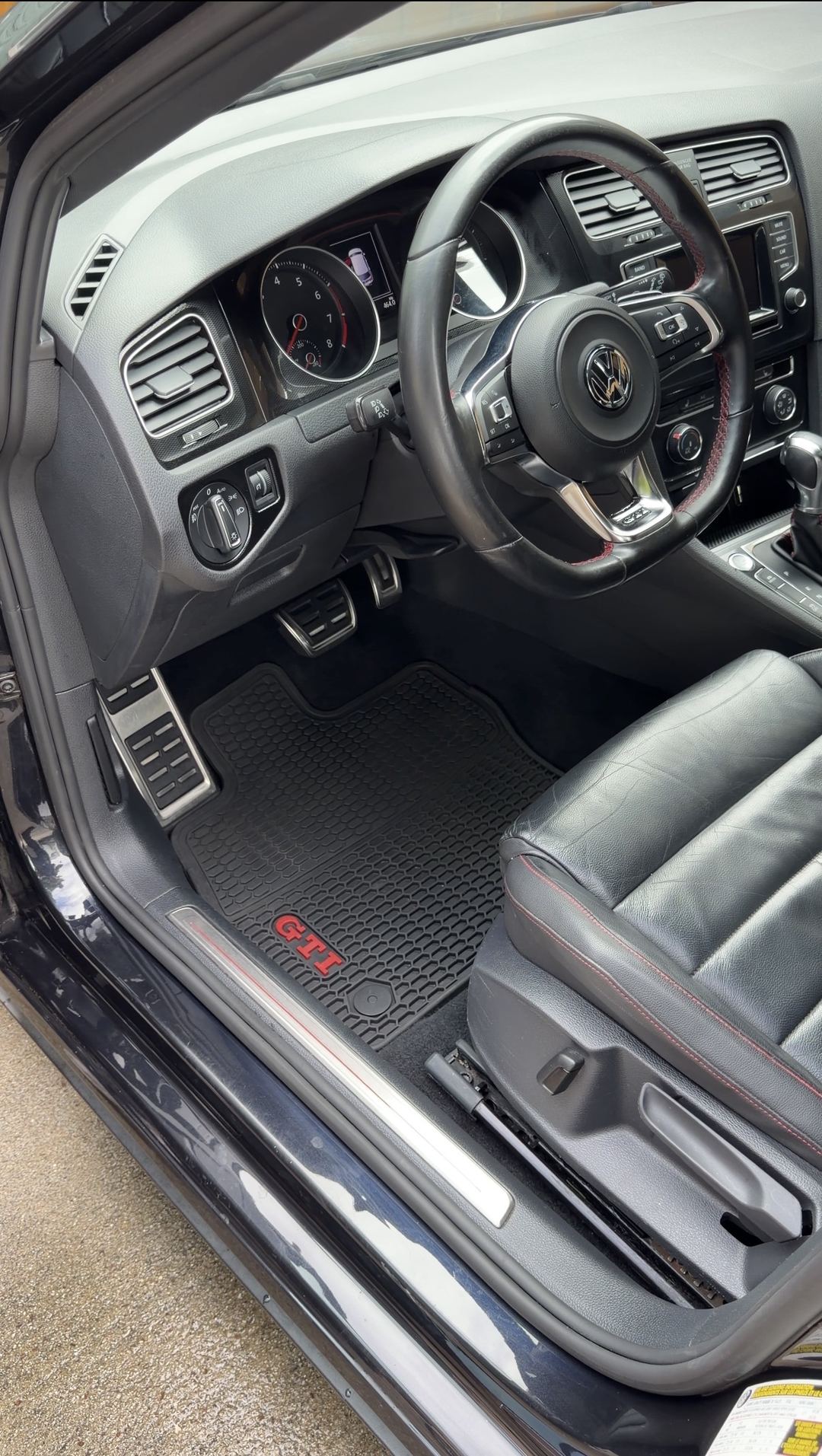 Driver footwell of a black VW GTI after cleaning, clean GTI rubber mat and sill