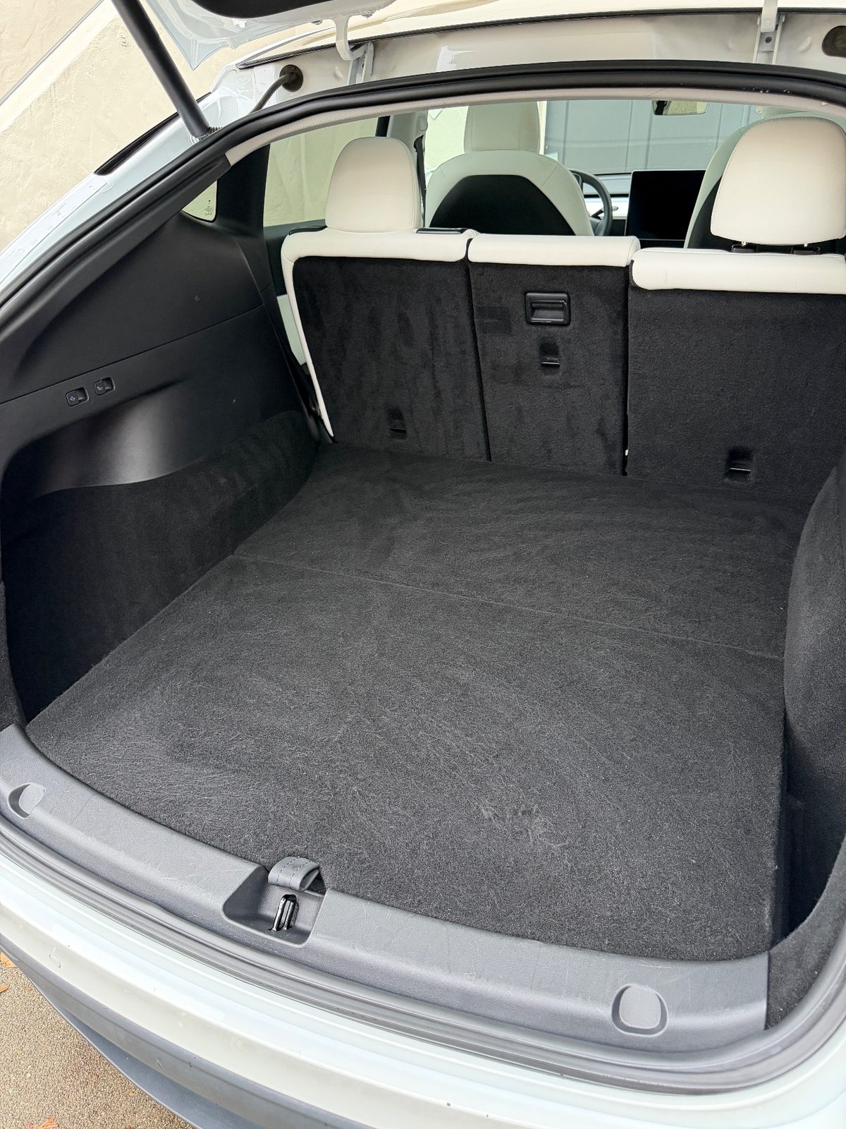 Cargo area of a white Tesla Model Y after detailing, with an even vacuumed carpet