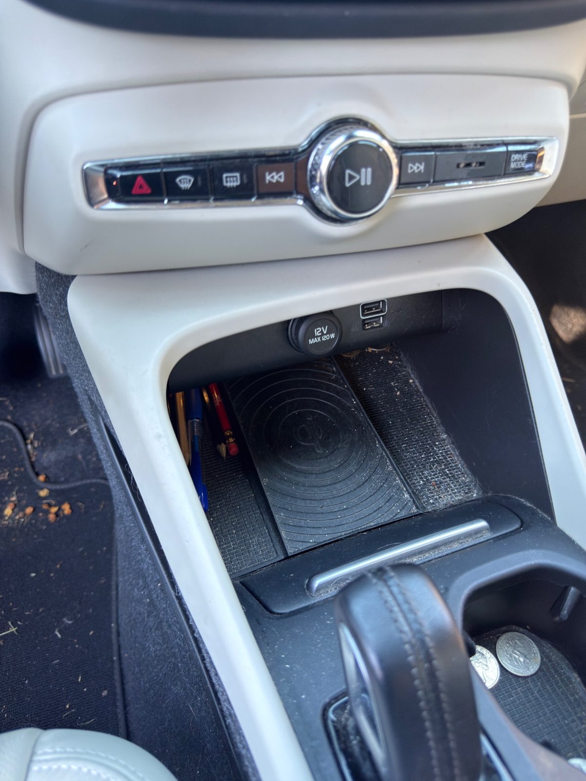 Dusty centre console cubby and wireless charging pad with pens and coins in a Volvo XC40 before detailing