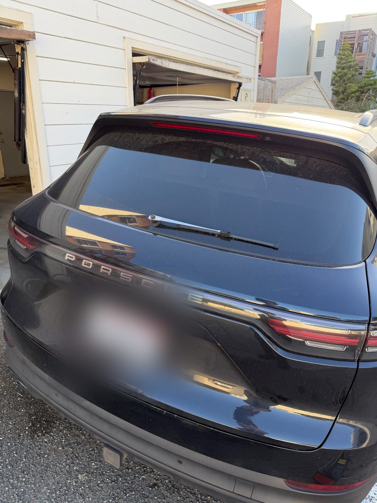 Rear of a dark blue Porsche Cayenne before washing, dusty tailgate and glass