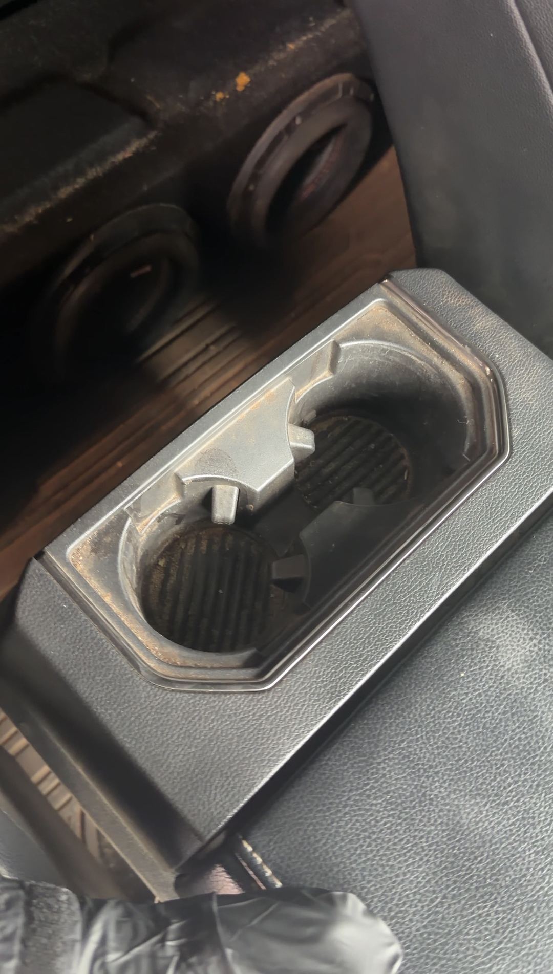 Rear cupholders of a Ford F-150 Raptor with dirt in the wells before cleaning