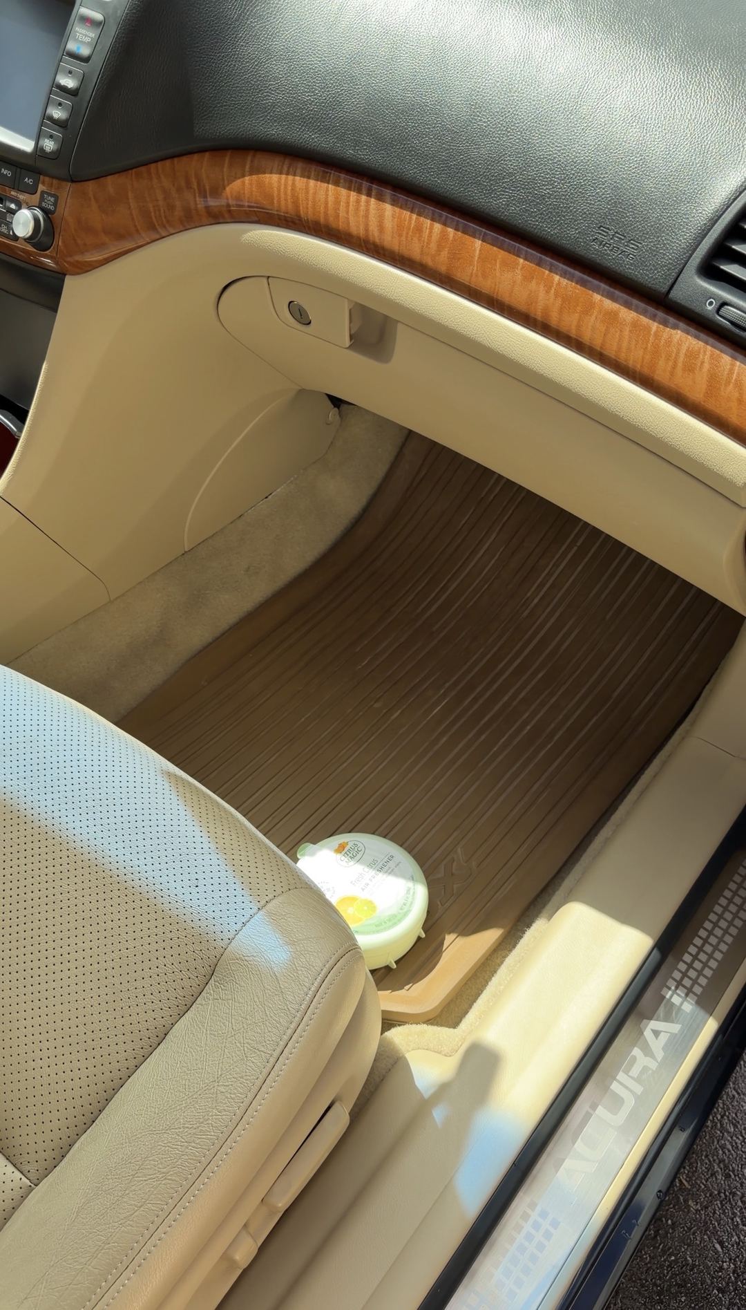 Cleaned front passenger footwell of an Acura TSX after detailing, with a clean branded rubber floor mat and an air freshener placed on it.