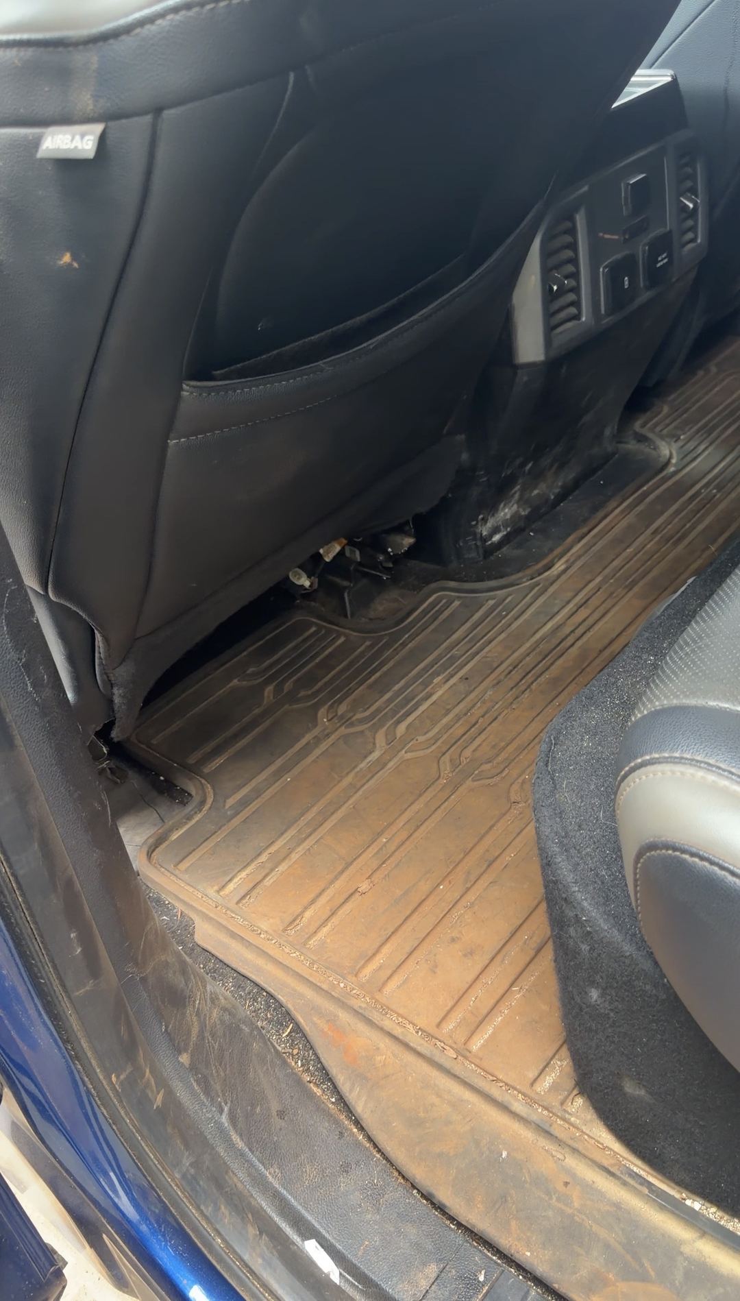 Rear footwell of a Ford F-150 Raptor with a mud-packed floor liner before cleaning