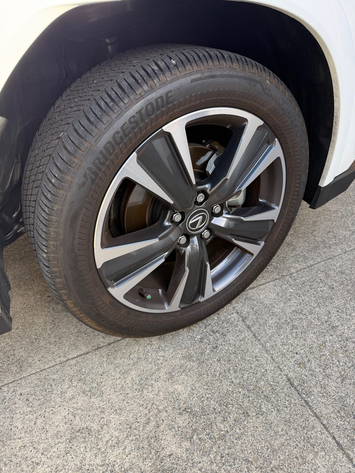 Wheel and tyre of a white Lexus UX before cleaning, covered in road film and brake dust