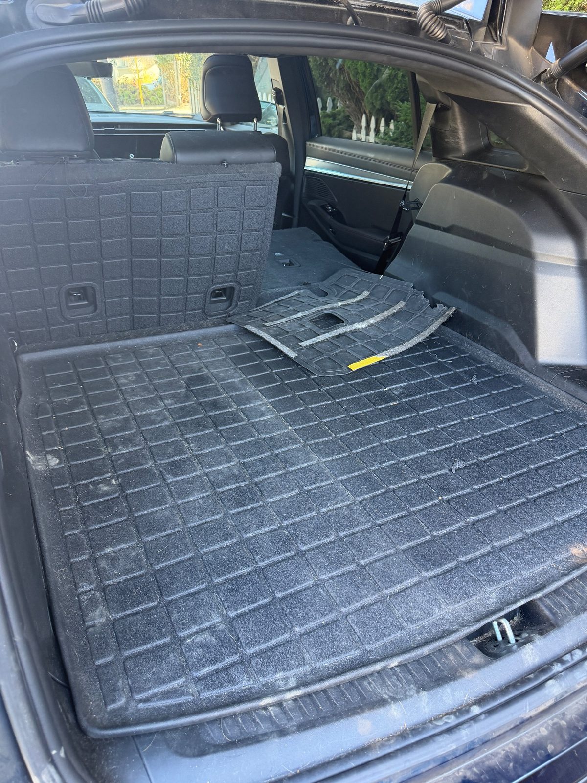 Cargo area of a dark blue Jeep Wagoneer S before detailing, with pet hair and dust on the cargo liner