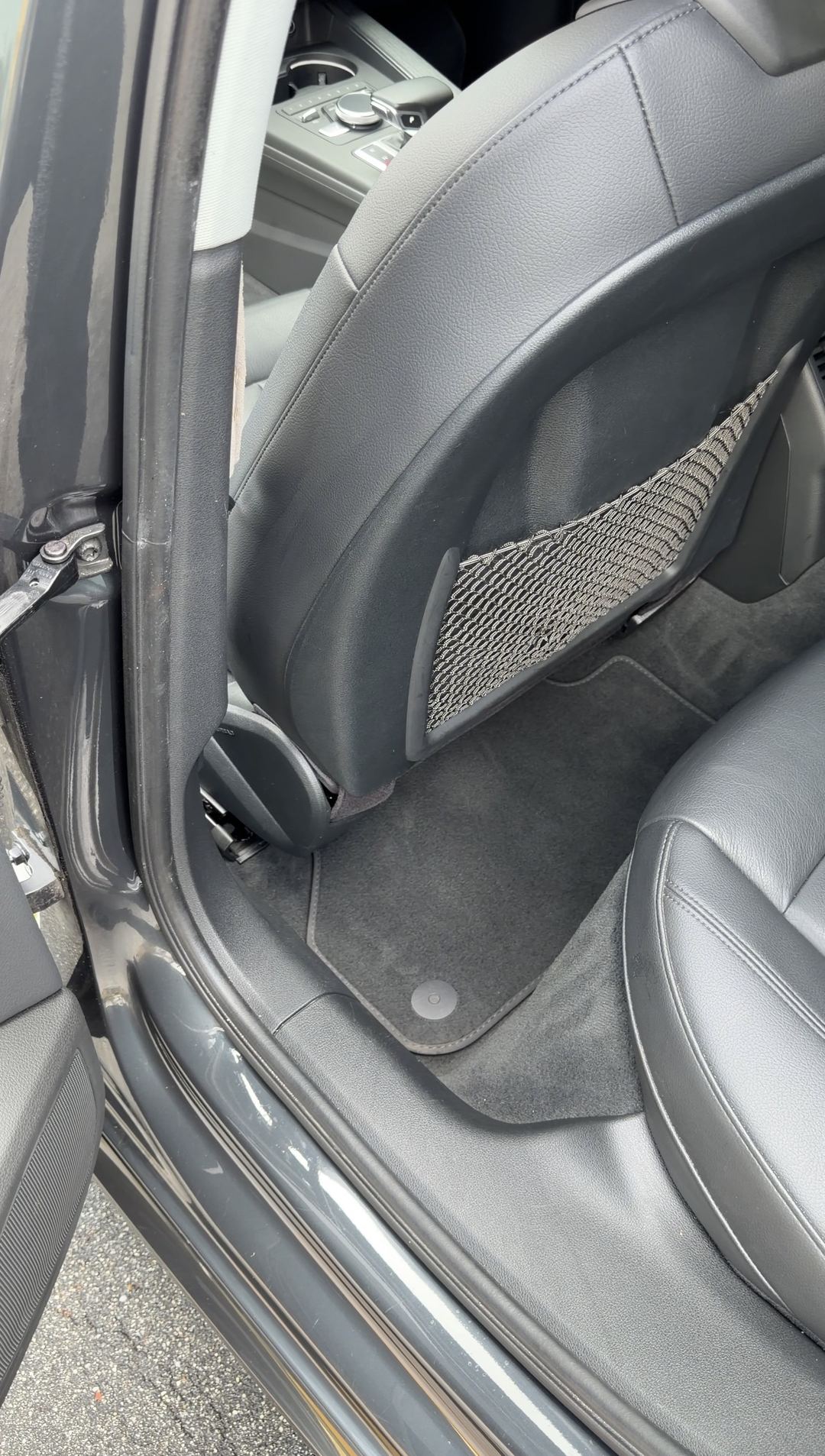 Vacuumed rear floor mat behind the driver seat of an Audi A4 with black leather seats
