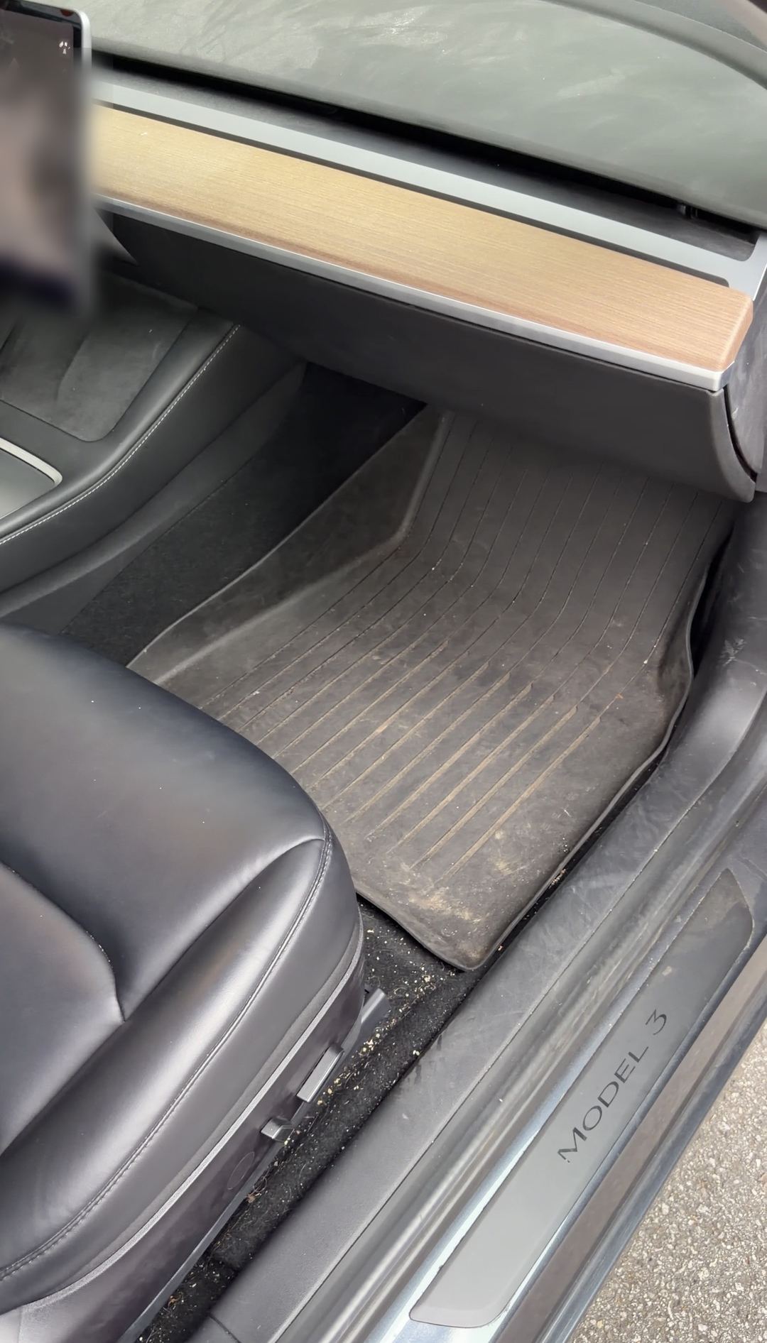 Tesla Model 3 front passenger footwell before cleaning, dust packed into the rubber mat