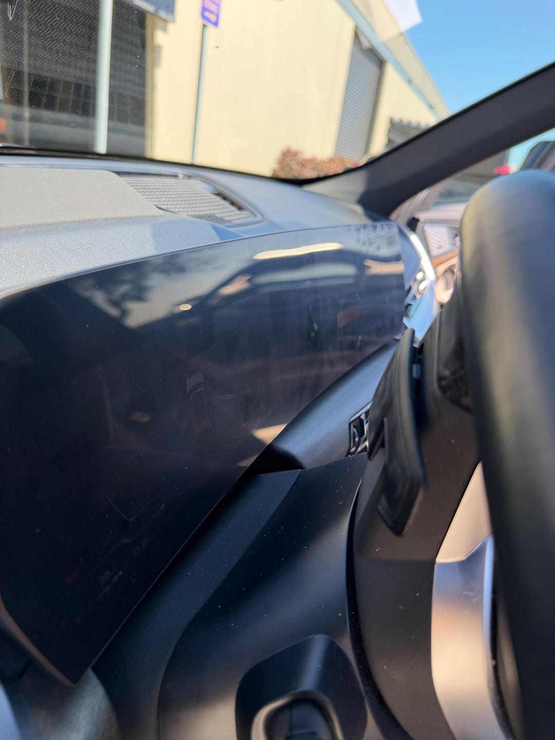 Instrument display of a grey BMW X1 before detailing, with dust specks on the screen
