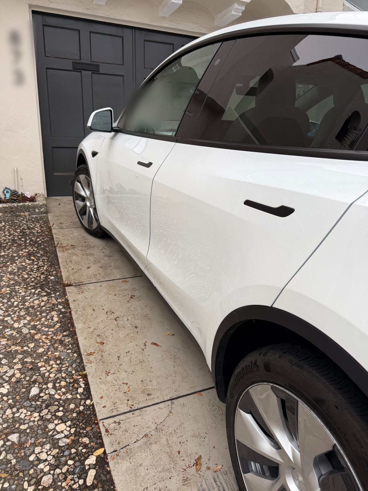 Driver side of a white Tesla Model Y after detailing, parked on a driveway