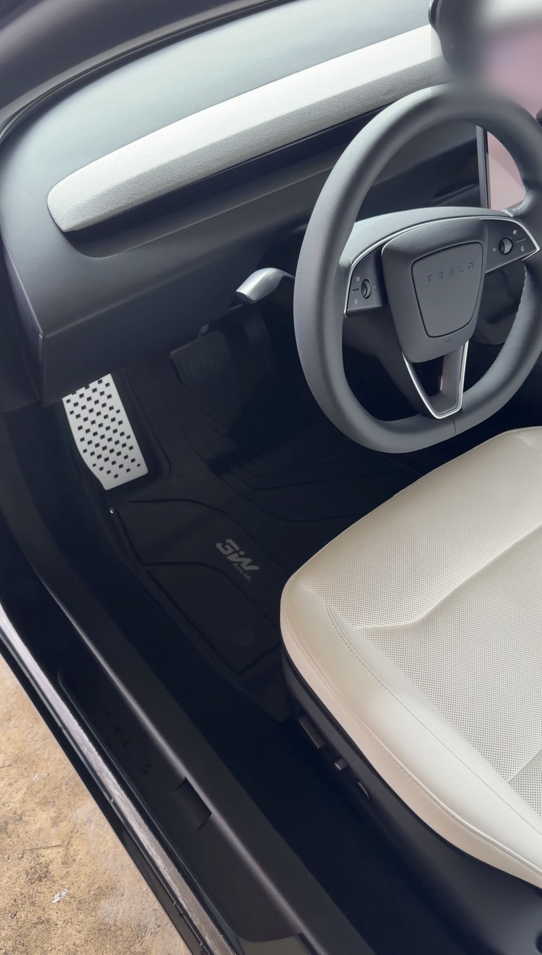 Cleaned driver's footwell and cream leather seat of a Tesla Model 3 after detailing