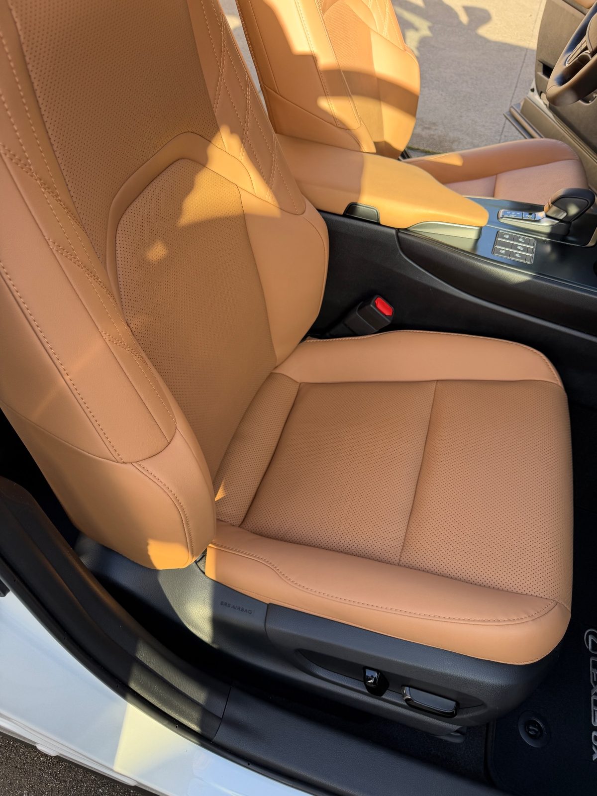 Clean cognac leather front seat of a white Lexus UX after detailing