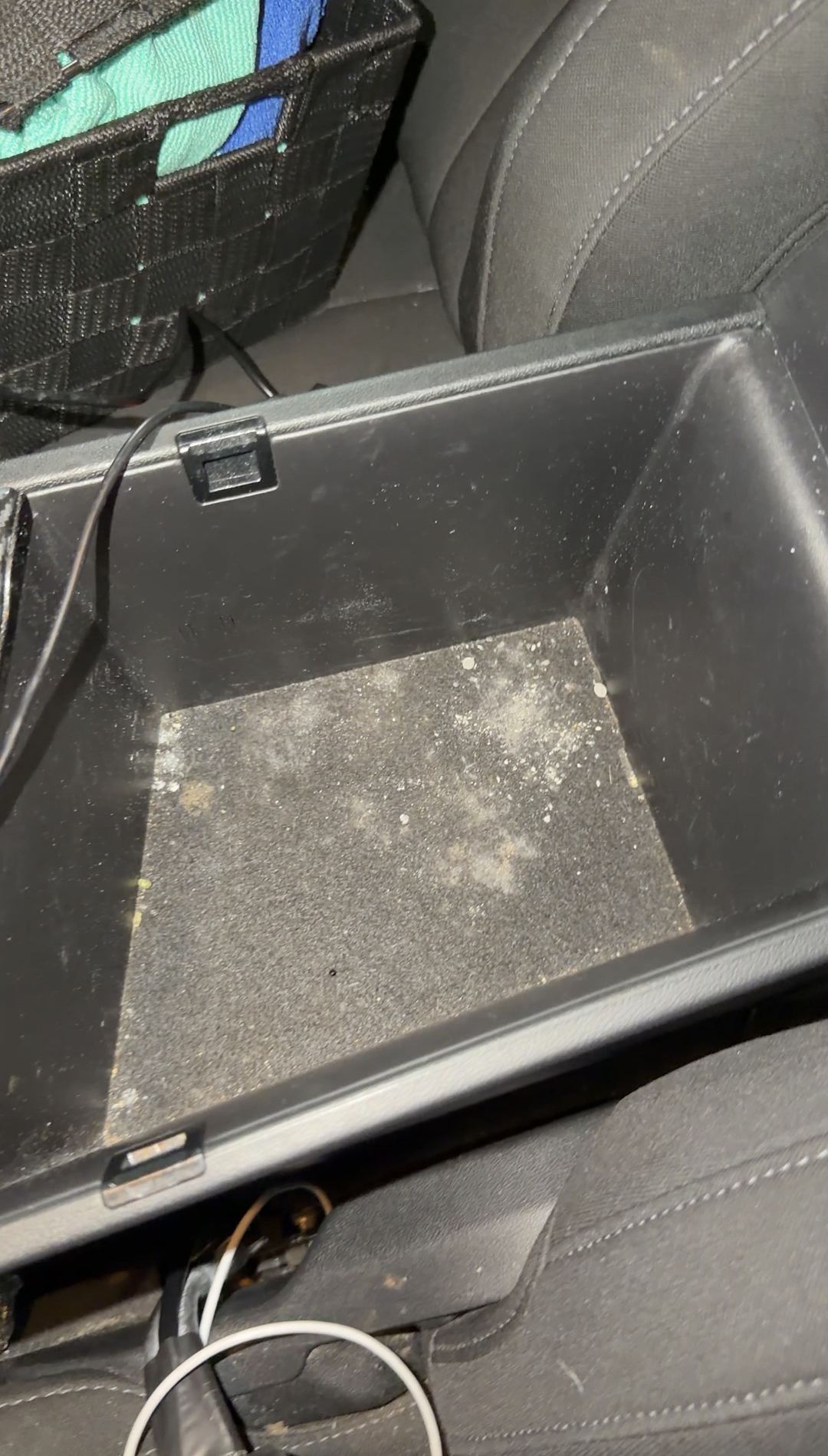 Dusty, stained armrest storage bin in a Hyundai Elantra before cleaning