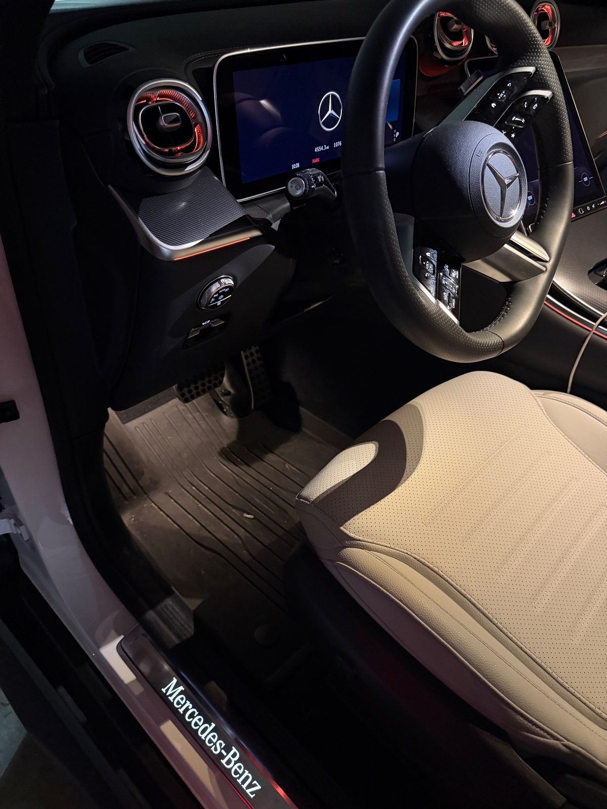 Driver footwell of a white Mercedes GLC before detailing, dusty rubber mat and debris