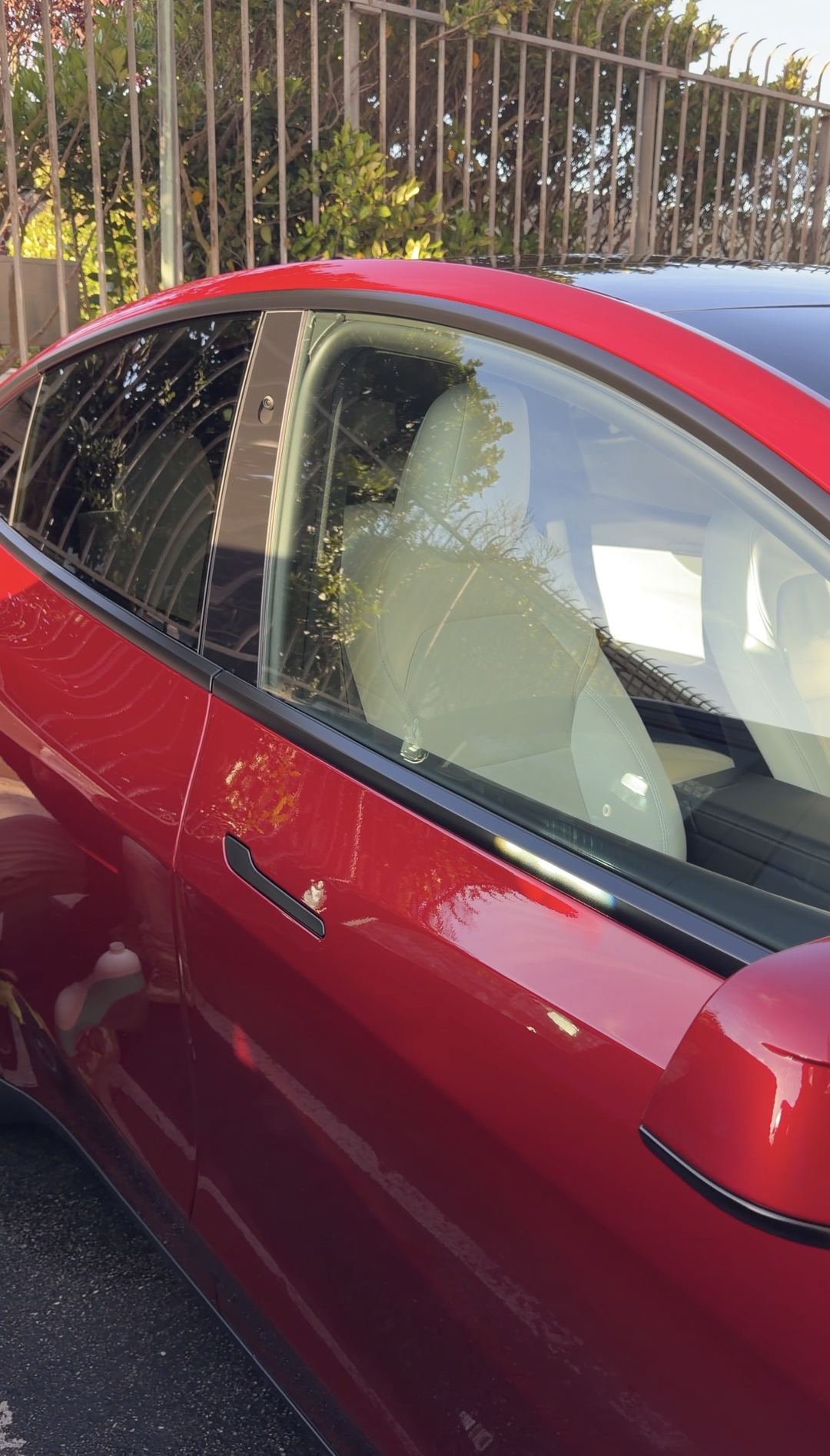 Clean front door and window of a red Tesla Model Y showing the white interior