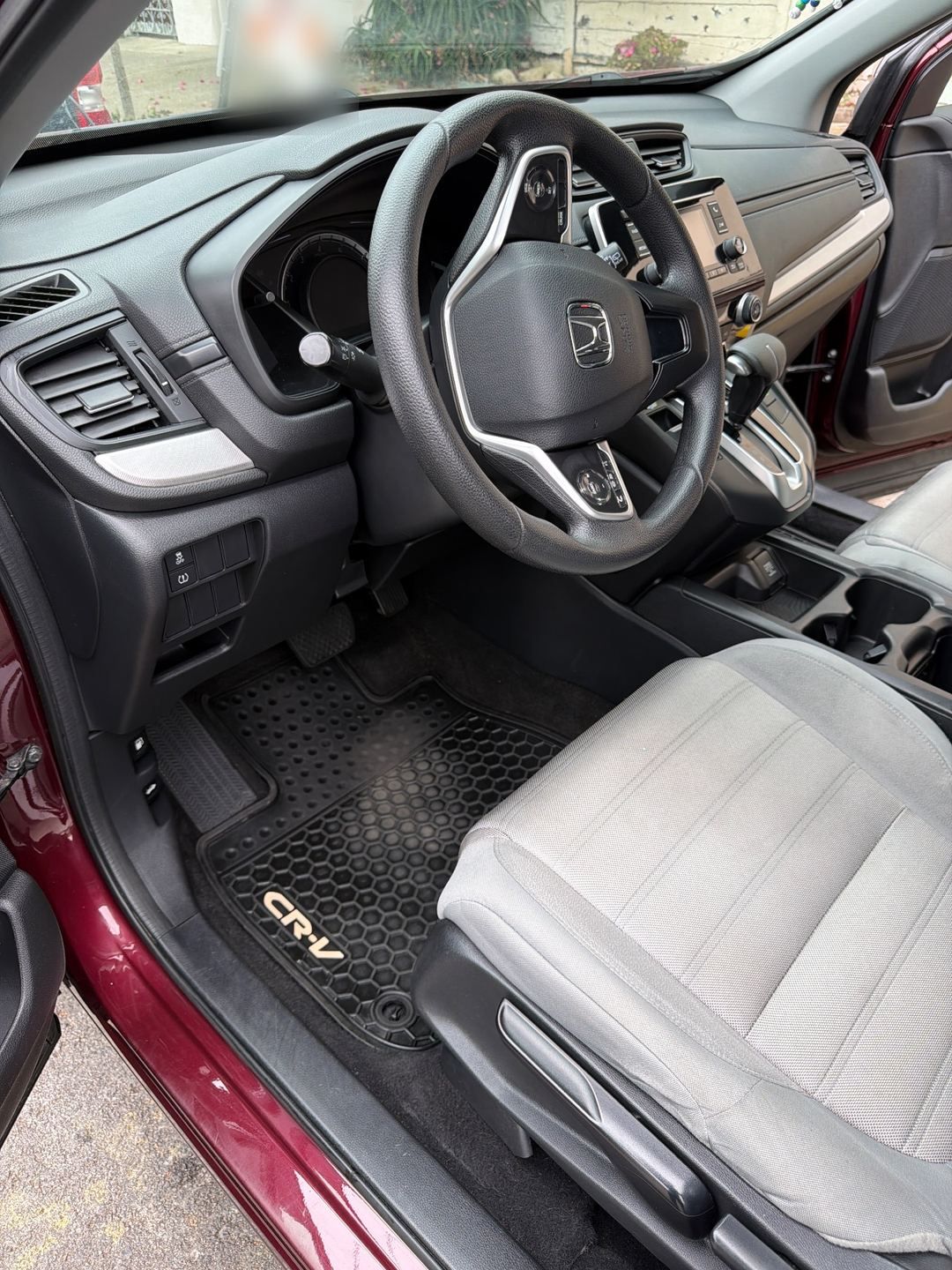 Driver footwell and dash of a maroon Honda CR-V after an interior detail, the rubber mat clean and black