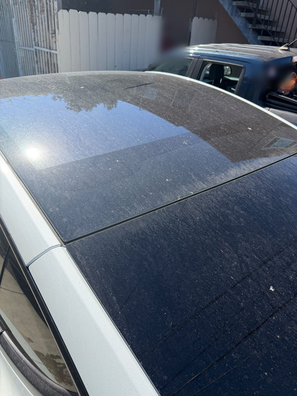 Dusty glass roof of a white Tesla Model Y before washing