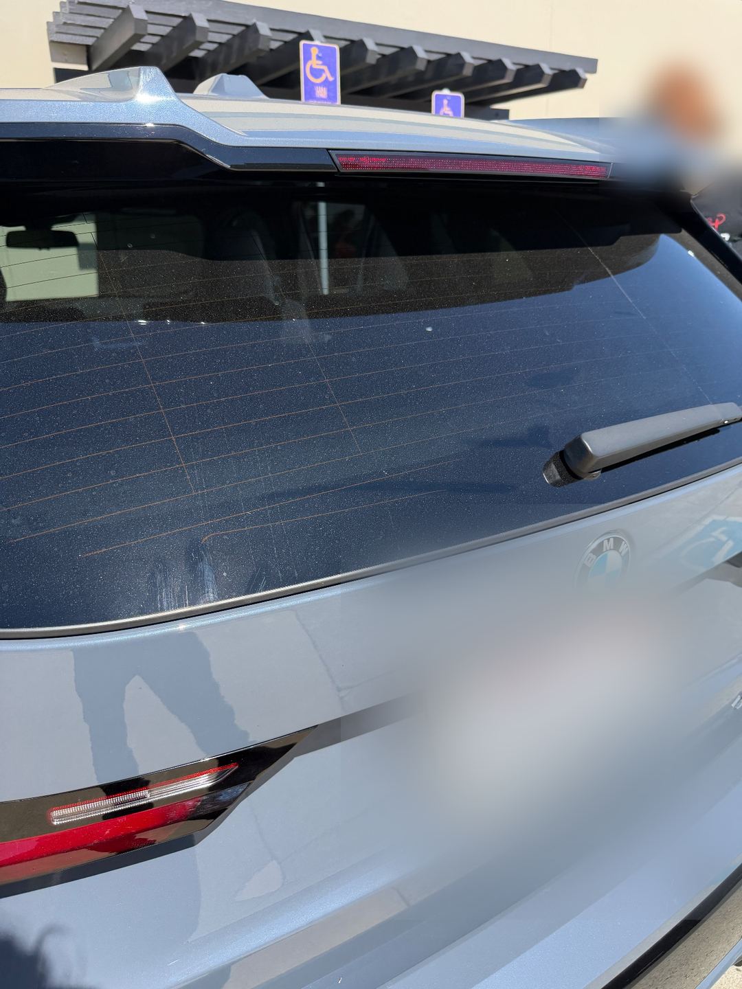 Rear glass of a grey BMW X1 before washing, covered in dust and water spots