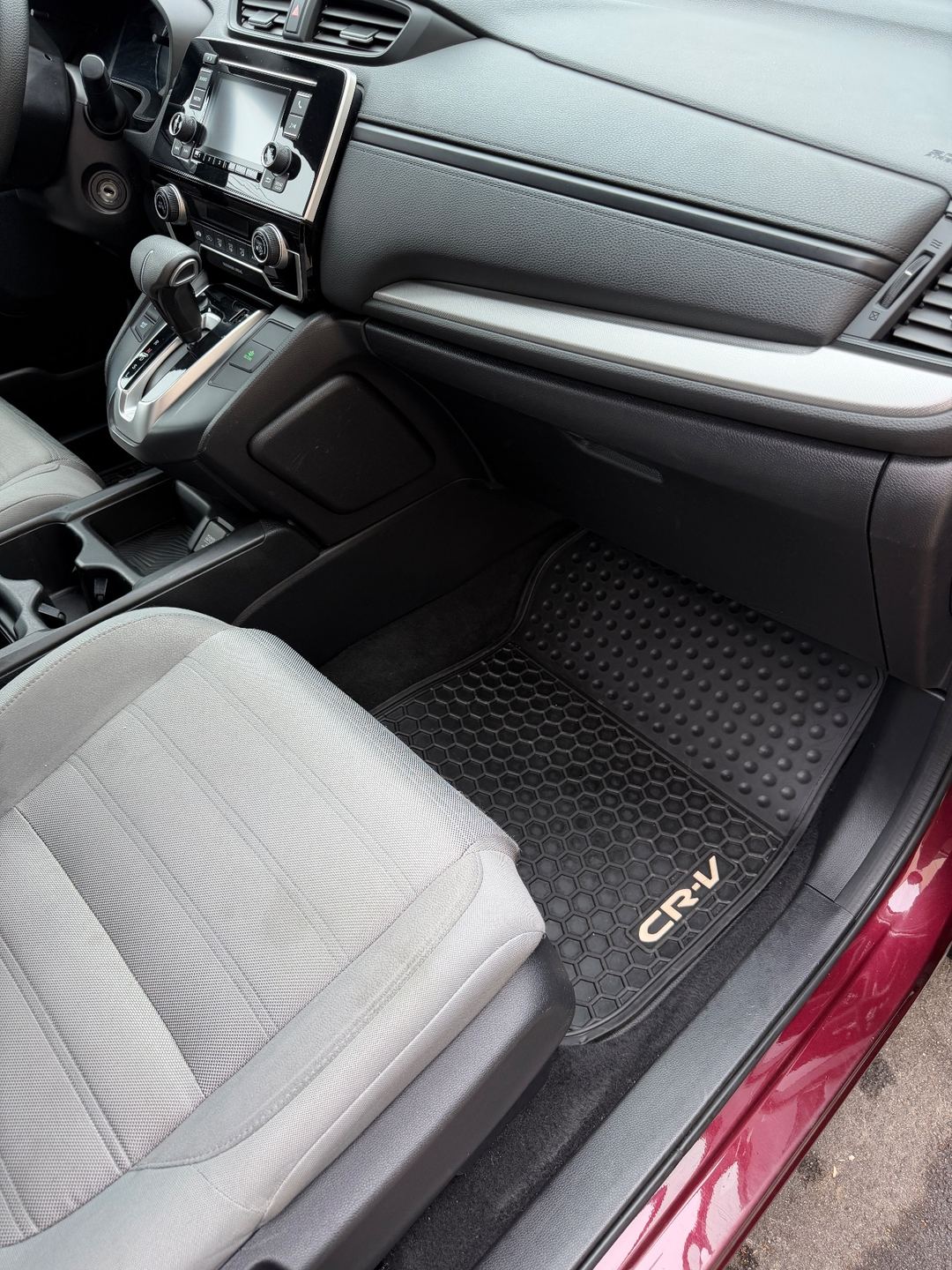 Front passenger footwell of a maroon Honda CR-V after detailing, the rubber mat clean and the cloth seat spotless