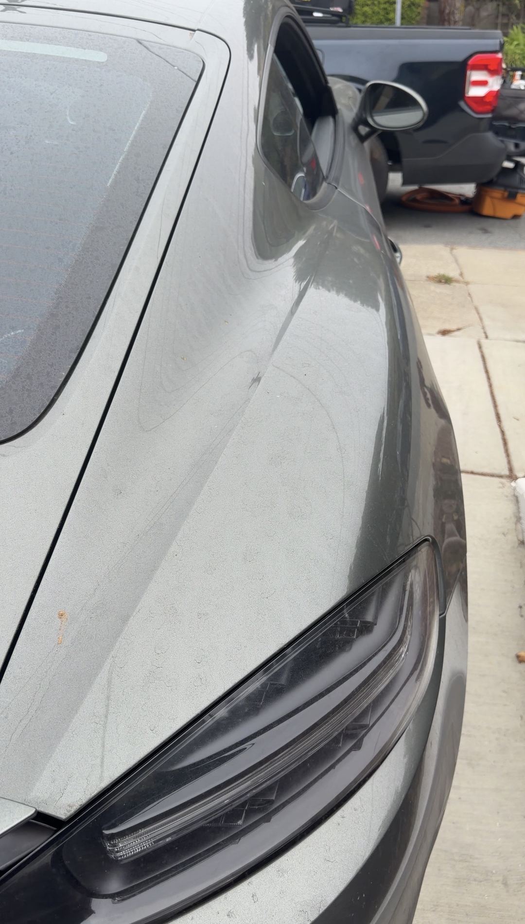 Dusty front end and hazed headlight of a green Porsche 718 Cayman S before a mobile detail.