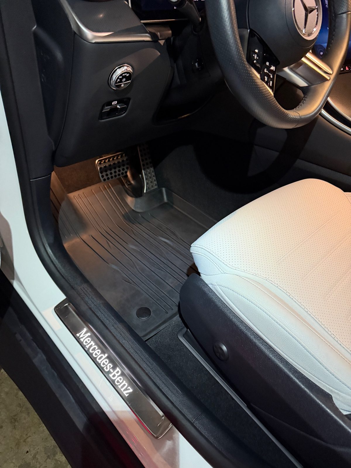 Driver footwell of a white Mercedes GLC after detailing, clean rubber mat and pedals