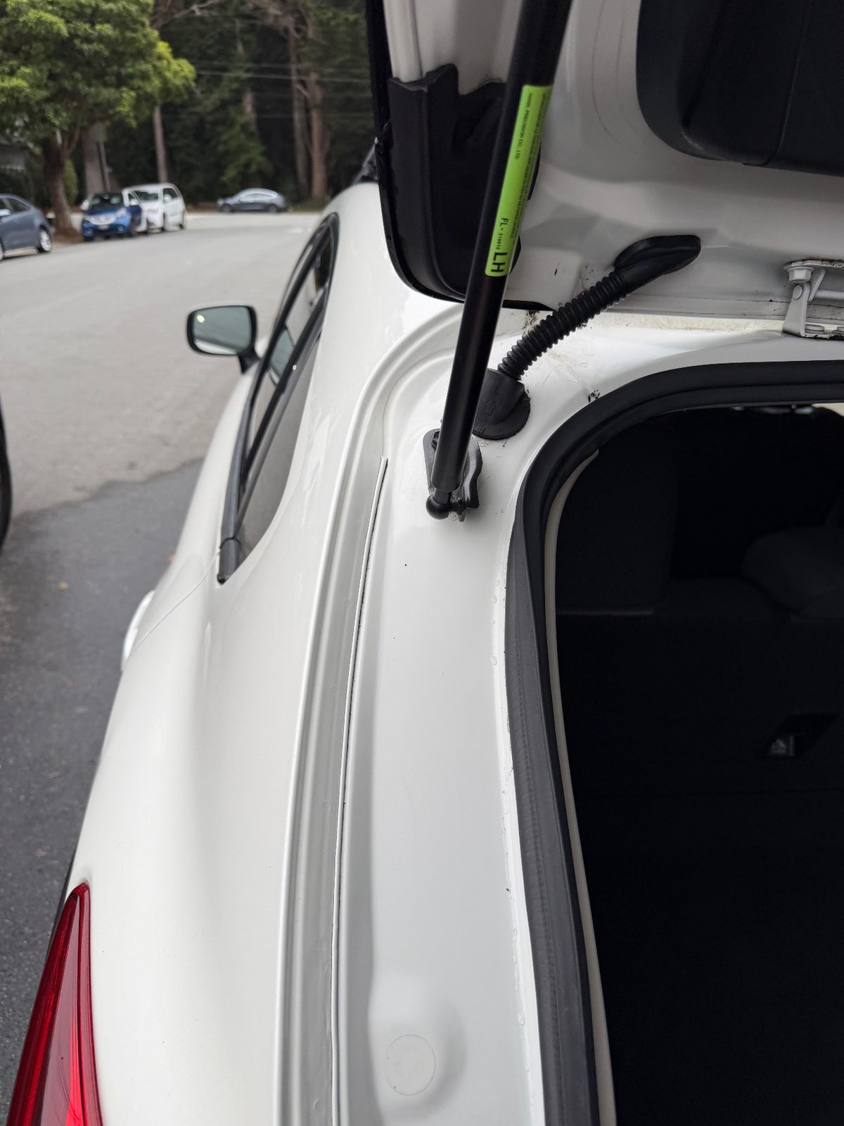 Left tailgate strut and hinge gutter clean after washing a white Subaru Crosstrek