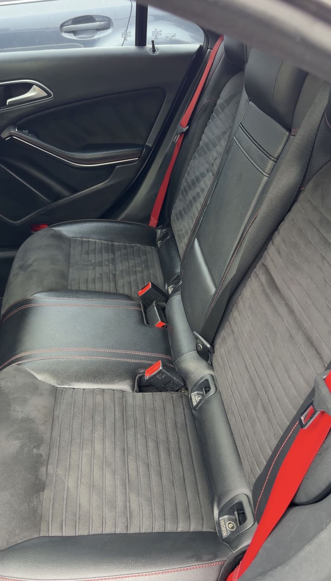 Freshly cleaned rear bench of a grey Mercedes-Benz CLA250 with grey microfibre seats and red seatbelts