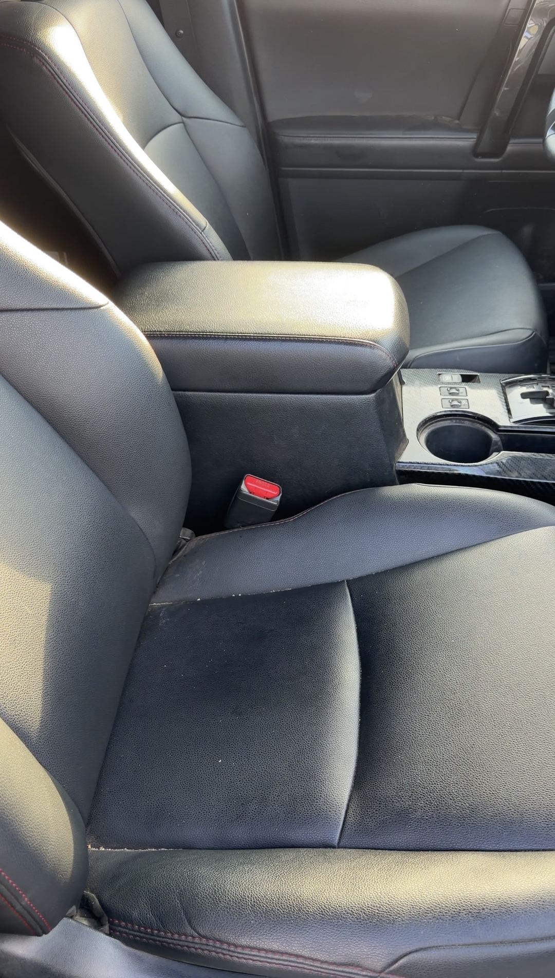 Dust-covered black front seats with red stitching in a Toyota 4Runner