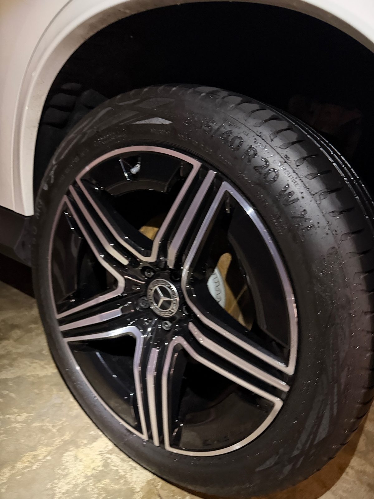Black and machined alloy wheel of a white Mercedes GLC after cleaning, glossy tyre