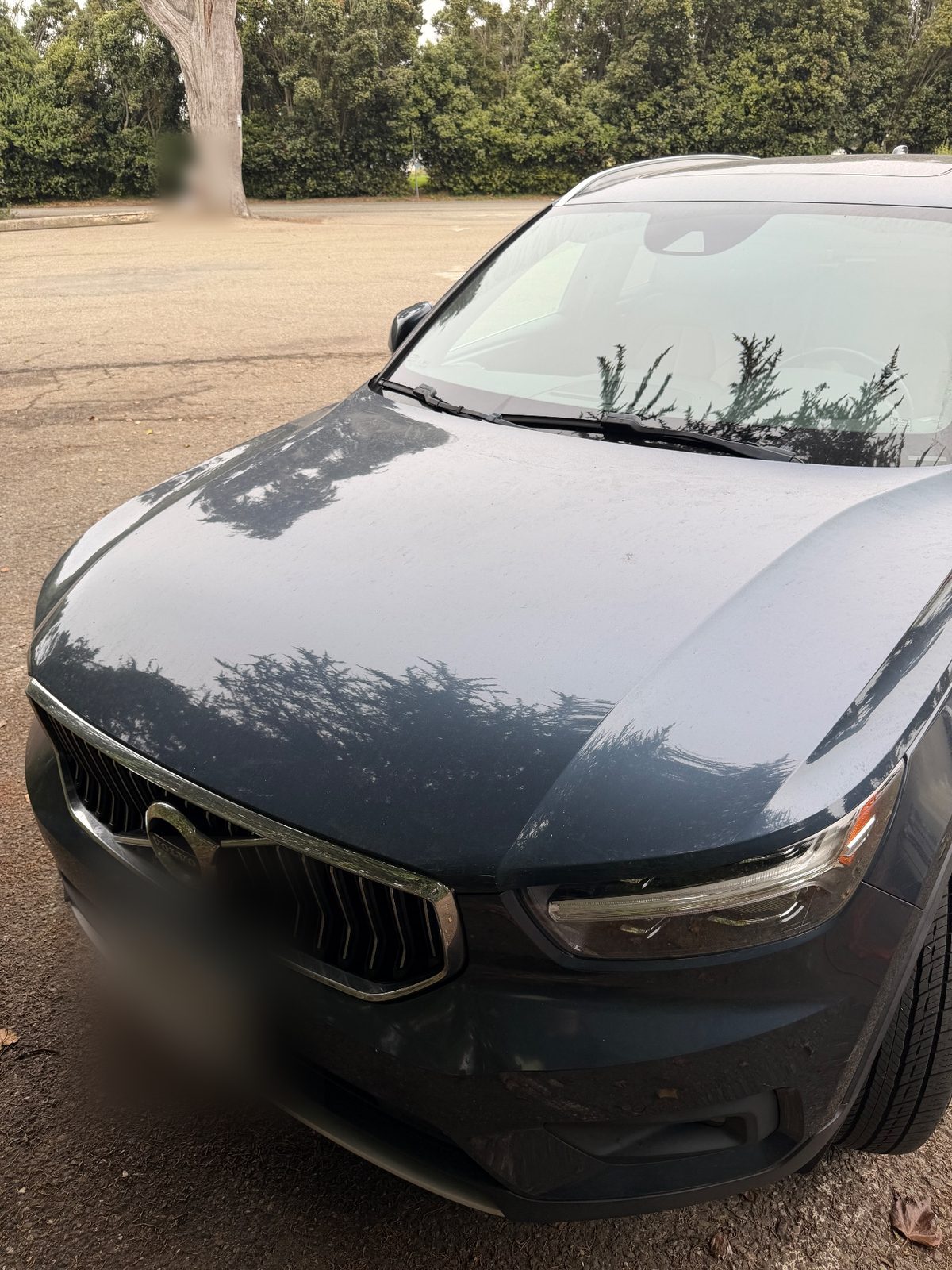 Front of a dusty Volvo XC40 in a parking lot before washing