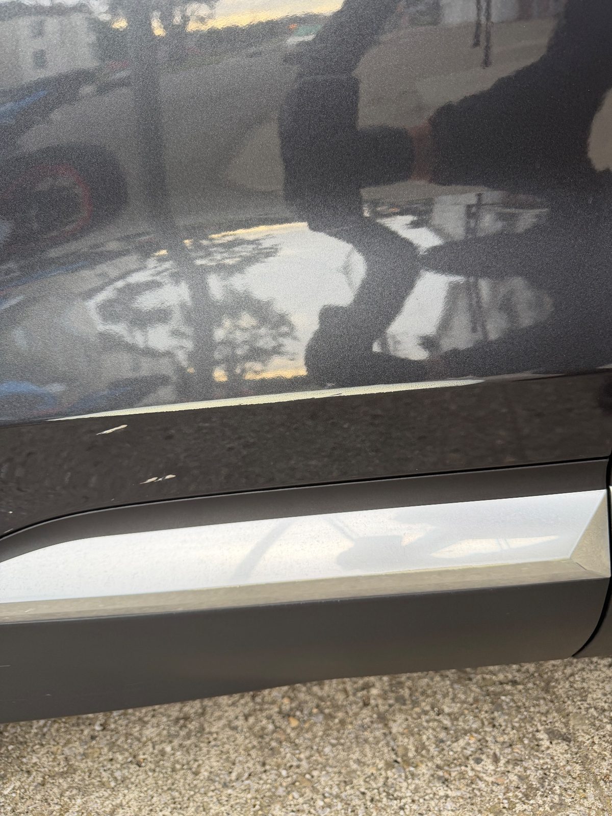 Paint chip flecks on the lower door of a grey Hyundai Santa Fe before detailing