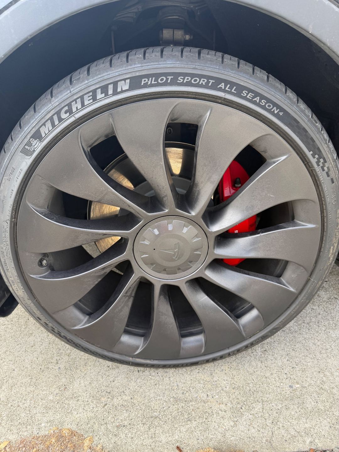 Michelin-shod 21-inch wheel with red brake caliper on a Tesla Model Y Performance before cleaning