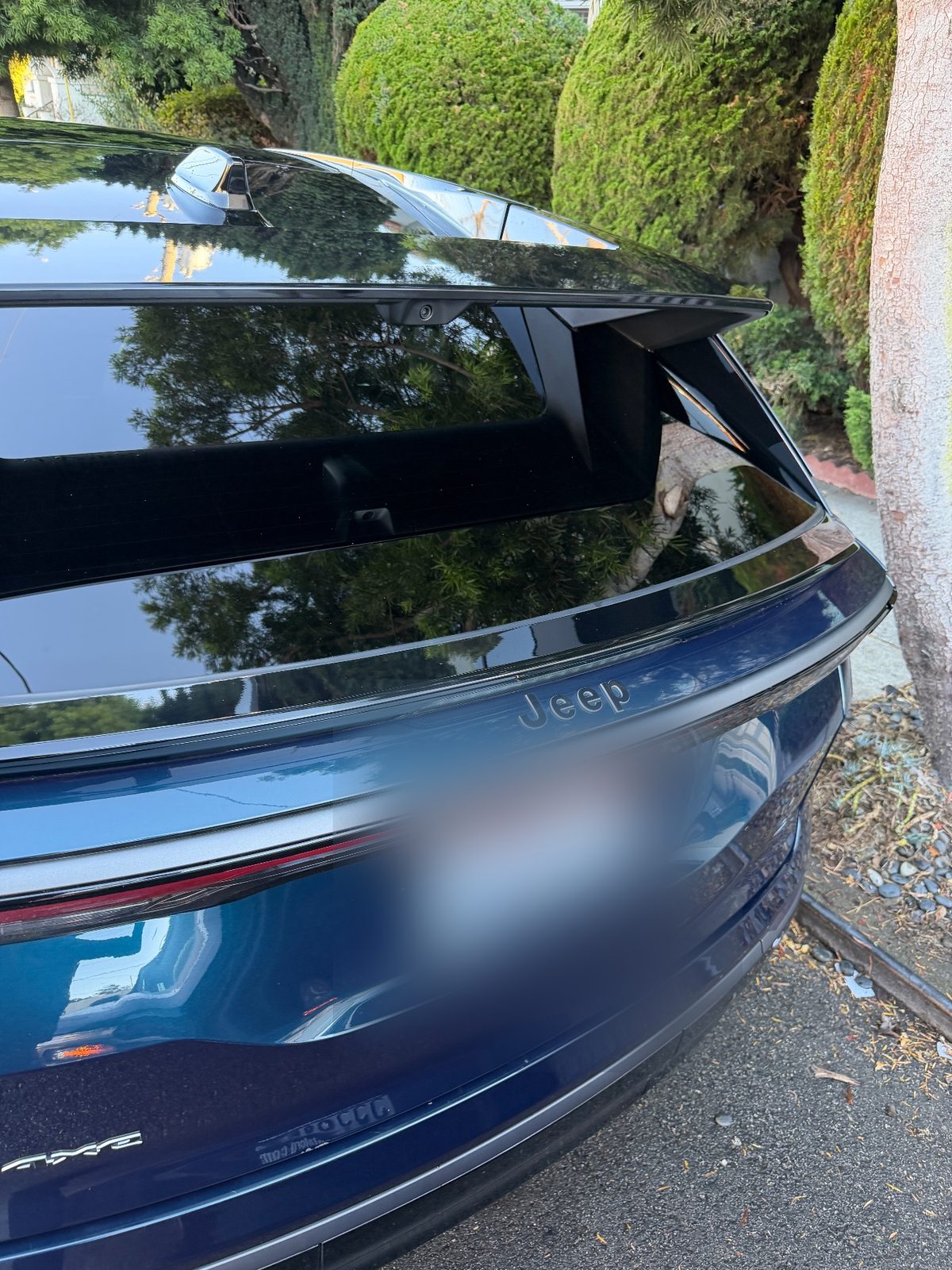 Clean glossy rear glass and tailgate of a dark blue Jeep Wagoneer S after detailing