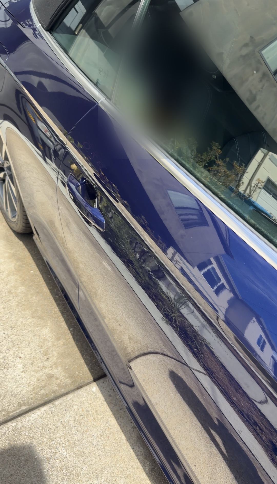 Glossy blue door of an Audi S5 Cabriolet reflecting houses across the street