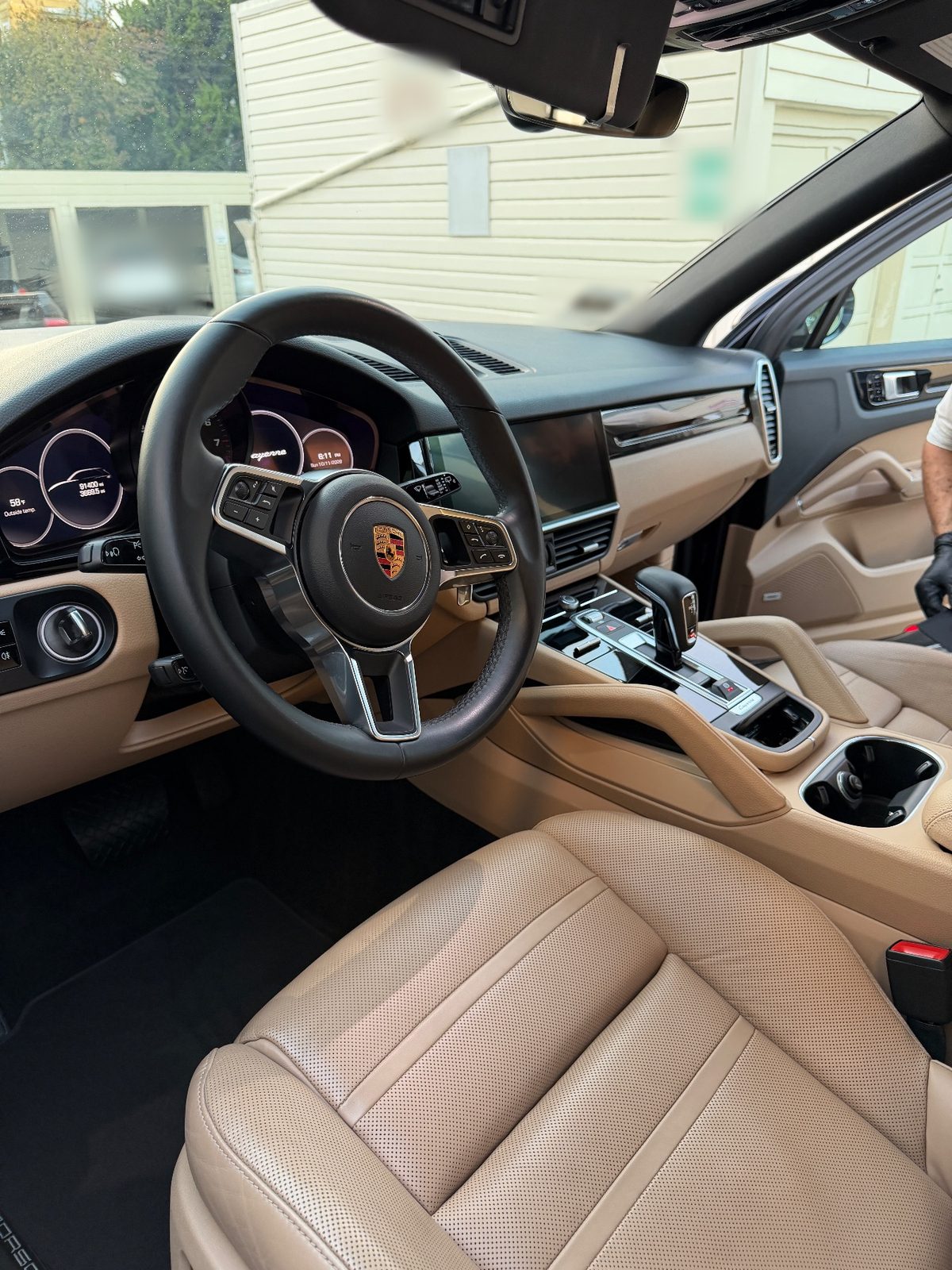 Clean front cabin of a Porsche Cayenne after detailing, tan leather and black steering wheel