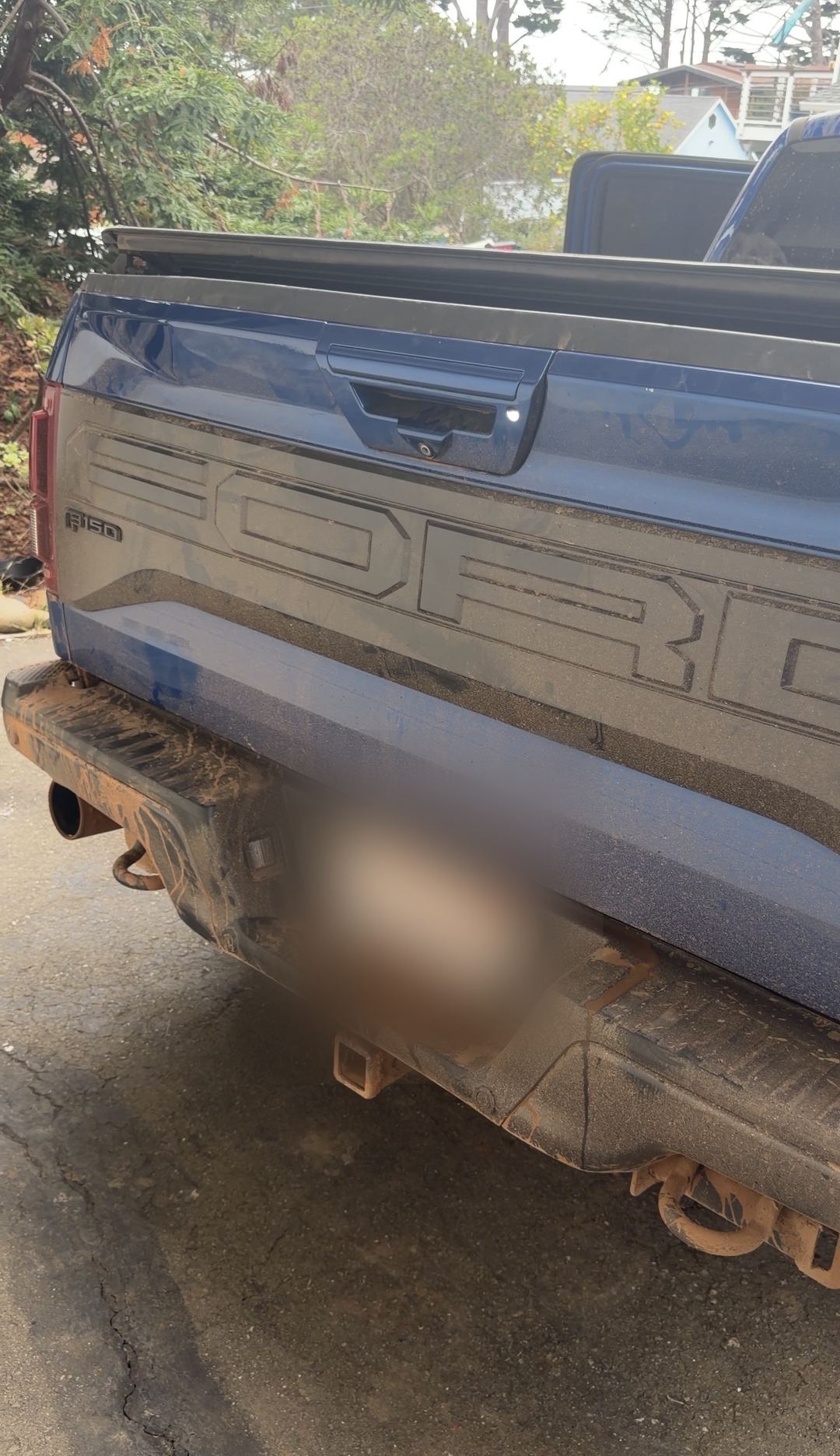 Rear bumper and hitch of a Ford F-150 Raptor packed with dried mud before a detail