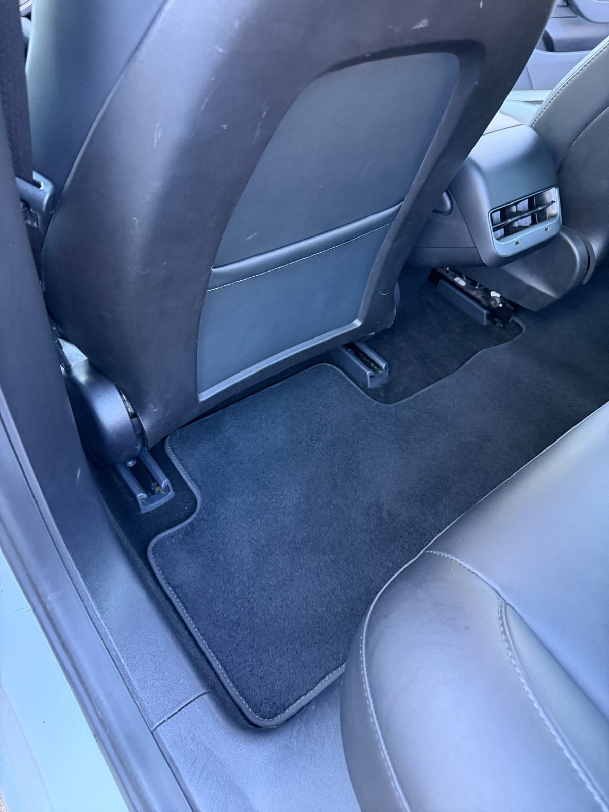 Rear floor mat of a white Tesla Model 3 after detailing, clean and free of hair