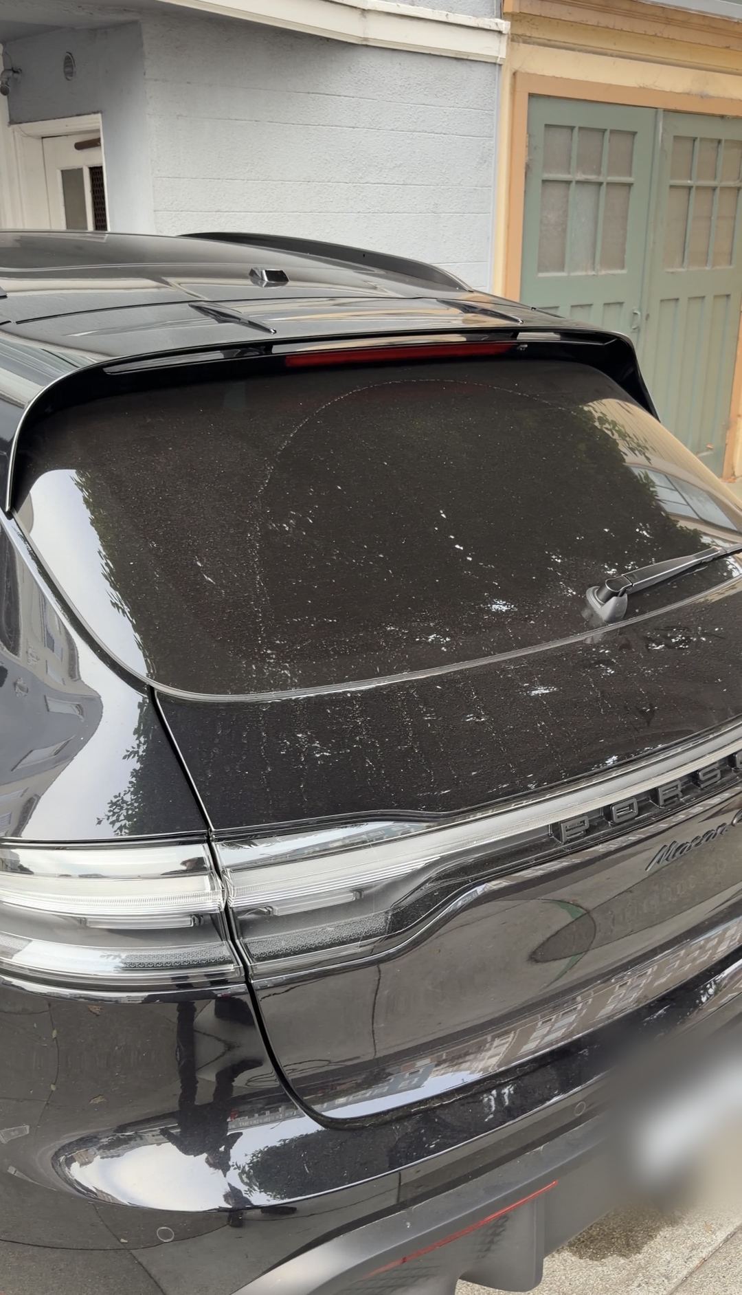 Dusty rear window and tailgate of a black Porsche Macan GTS before an SF City Wash exterior detail.
