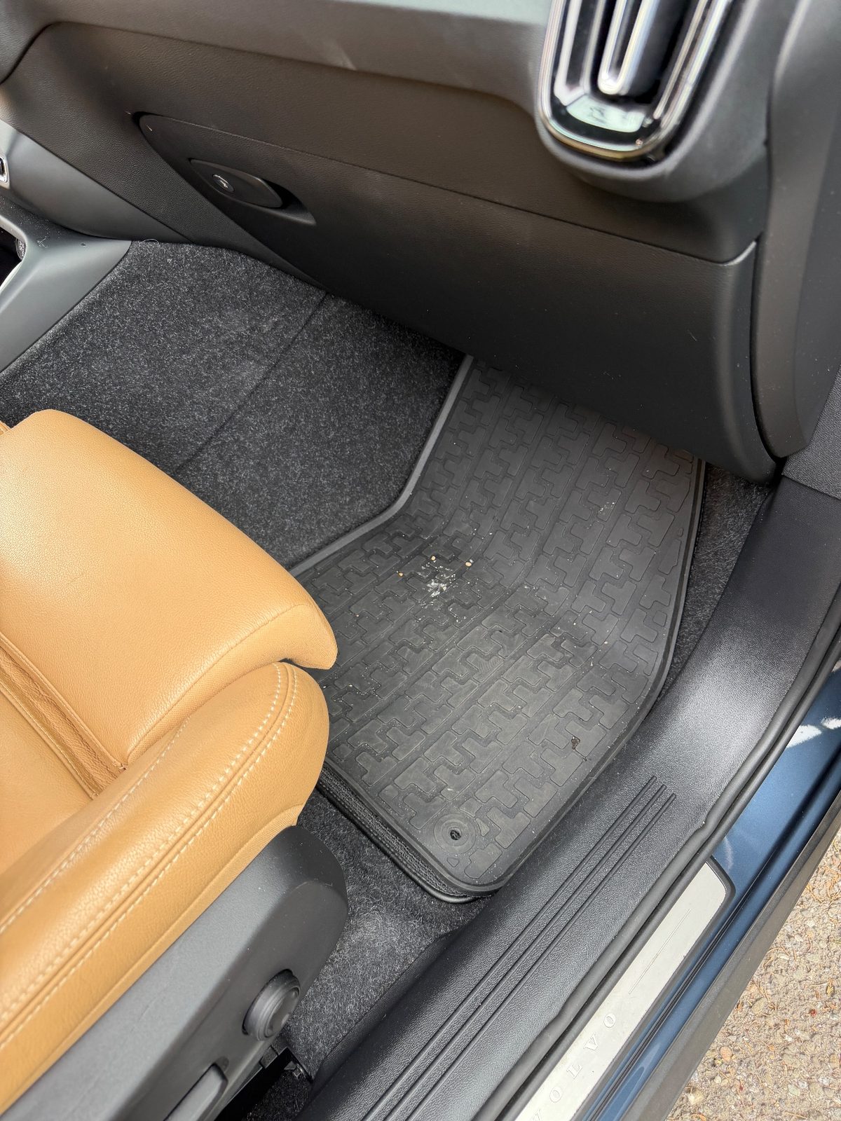 Front passenger footwell of a Volvo XC40 before detailing, with crumbs and debris on the rubber mat