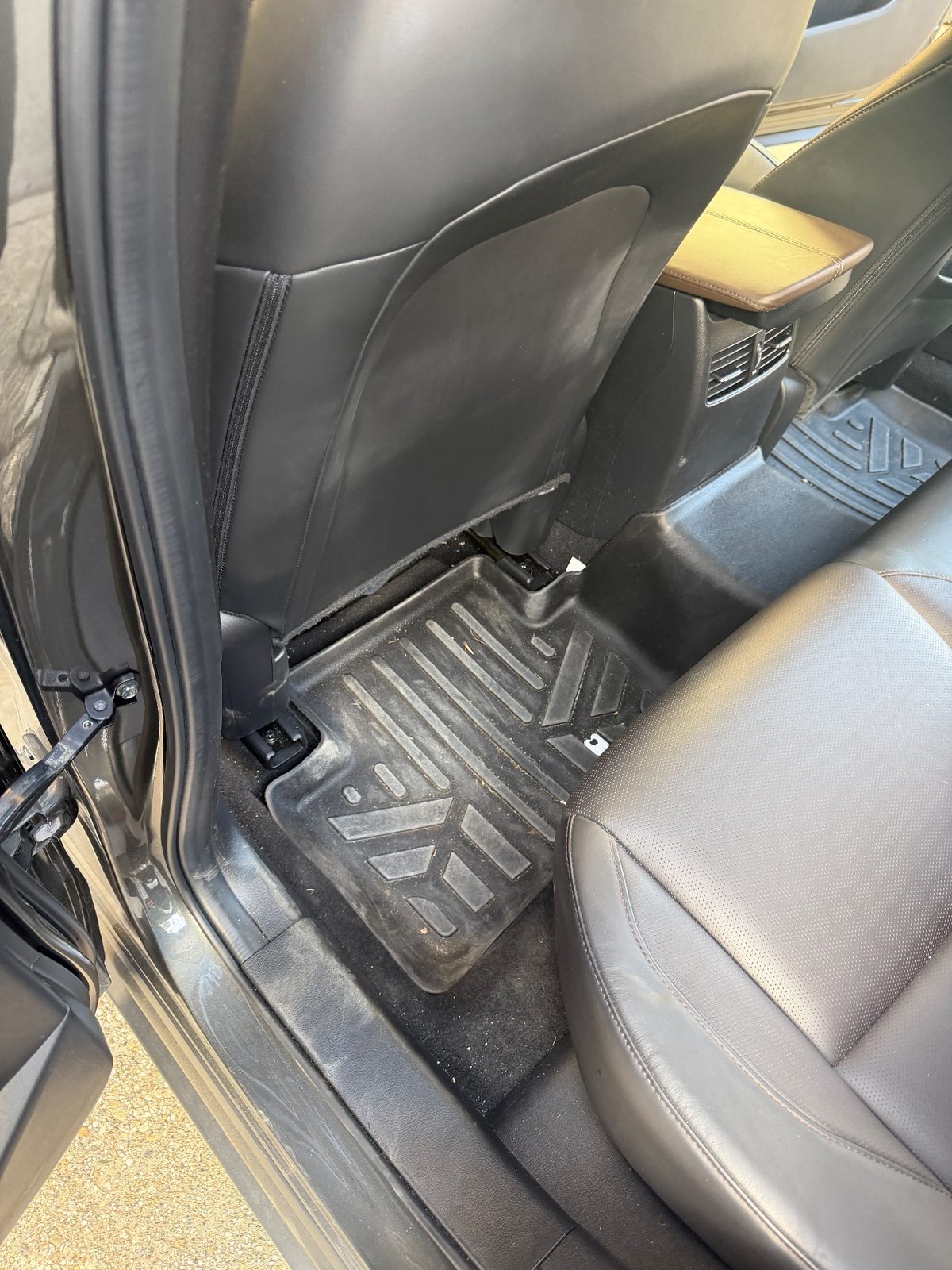 Rear footwell of a grey Mazda CX-30 before cleaning, liner dirty with grit and debris