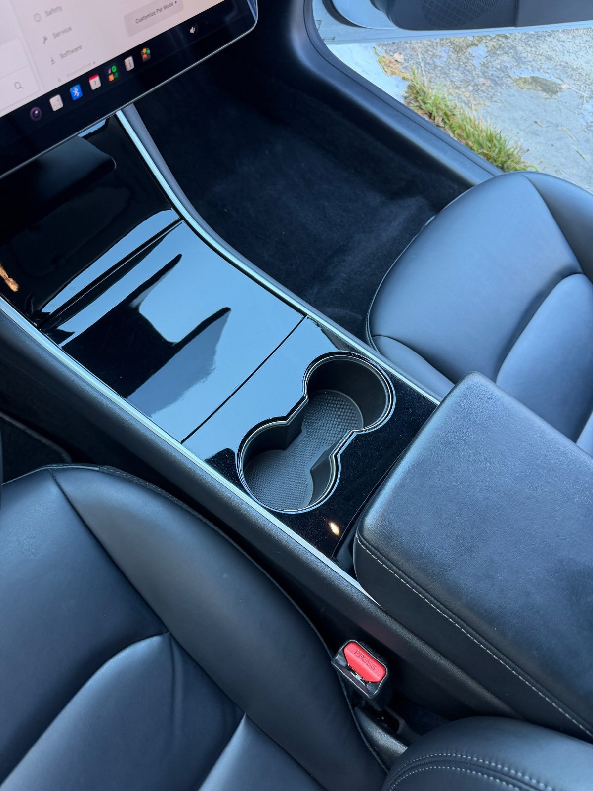 Clean gloss-black centre console of a white Tesla Model 3 after detailing