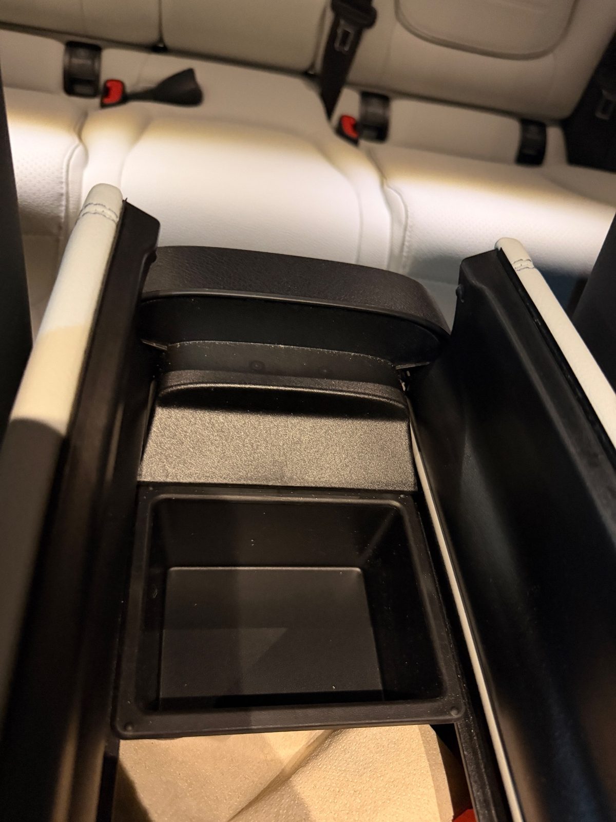 Opened centre armrest bin of a white Mercedes GLC before cleaning, dust and debris inside