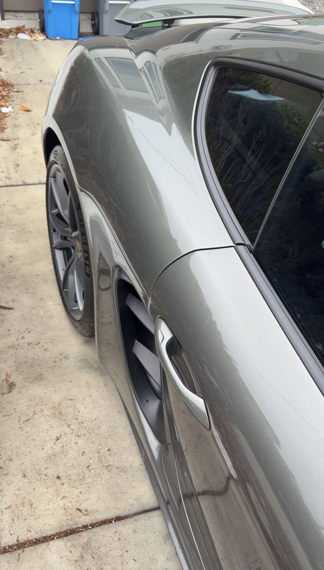 Clean rear quarter and side air intake of a green Porsche 718 Cayman S after a mobile detail.