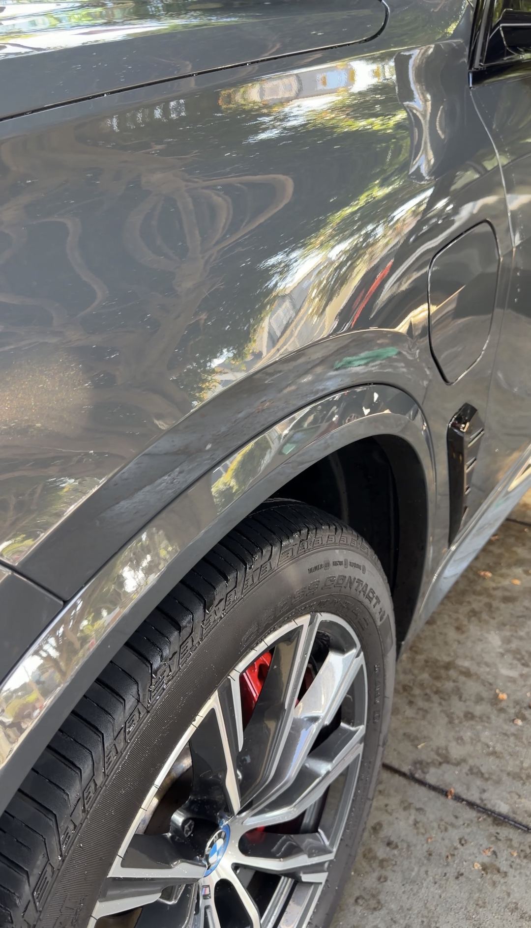 Right rear quarter and wheel of a dark grey BMW X5 after detailing, with a red brake caliper behind the polished spokes