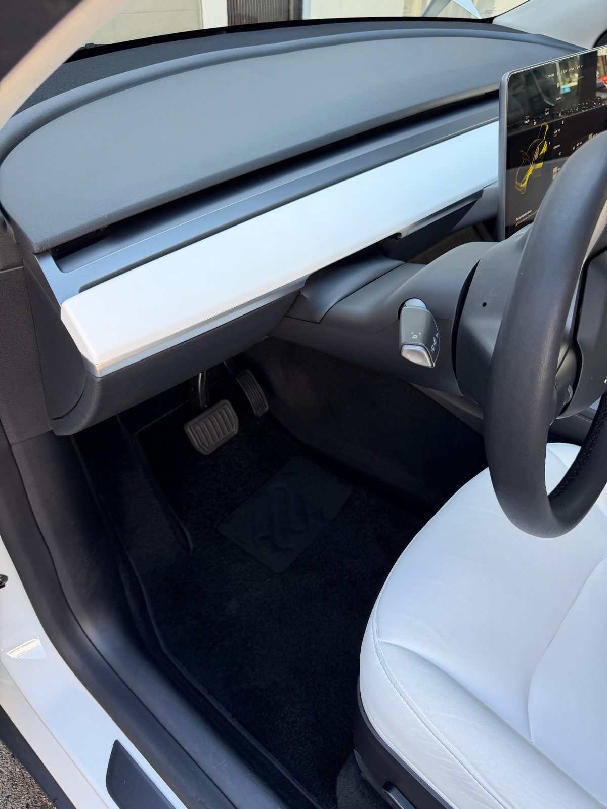 Clean driver footwell of a white Tesla Model Y after detailing