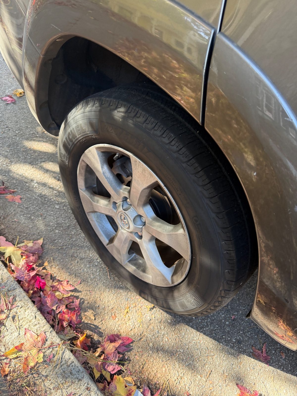 Dusty rear alloy wheel at the curb on a 2011 Toyota RAV4 before cleaning