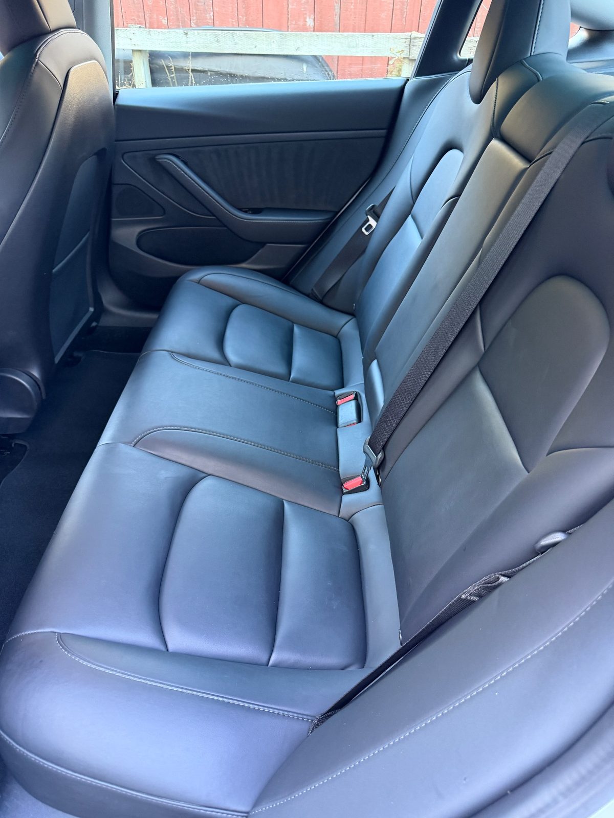 Rear bench seat of a white Tesla Model 3 after detailing, clean black leather